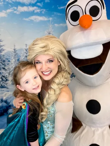 Elsa and Olaf posing with a young girl holding an Anna doll at a library visit