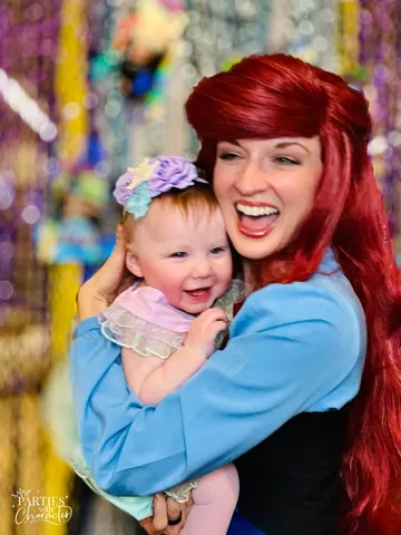 Ariel laughing with a delighted baby against a sparkly backdrop