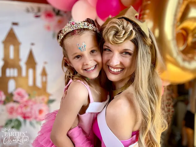 Aurora posing with a girl in a tiara in front of a castle backdrop