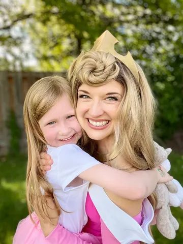 Aurora hugging a girl holding a stuffed unicorn outdoors
