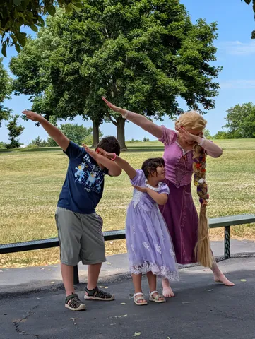 Rapunzel and two children striking a playful pose under a tree