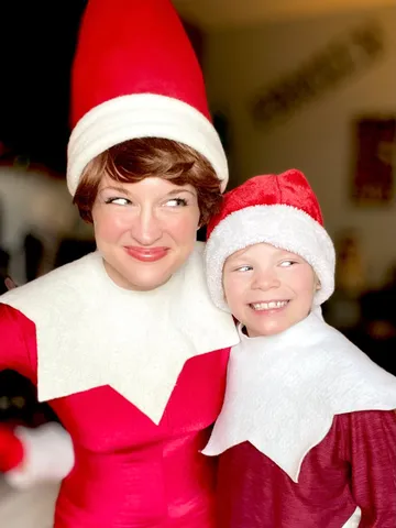 Elf on the Shelf posing with a preteen boy also dressed in a red elf costume