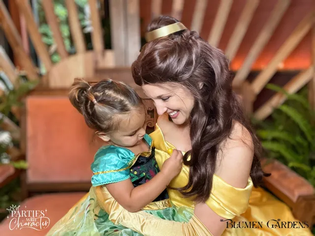 Belle holding a toddler in a teal dress close for a hug
