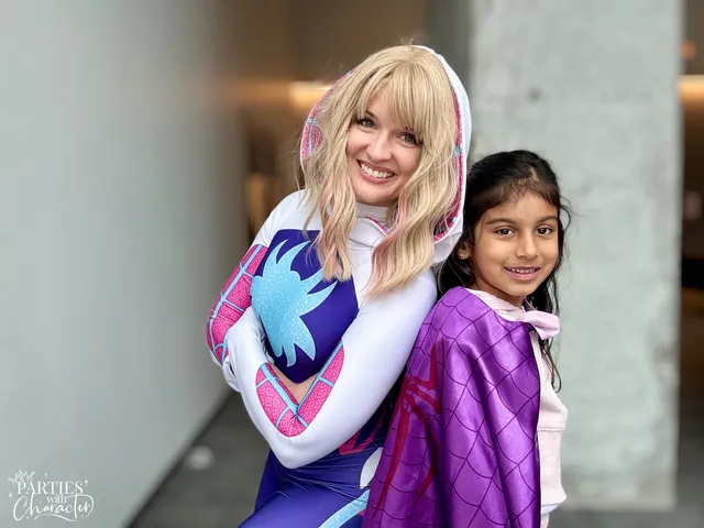Ghost Spider hugging a young girl wearing a purple superhero cape