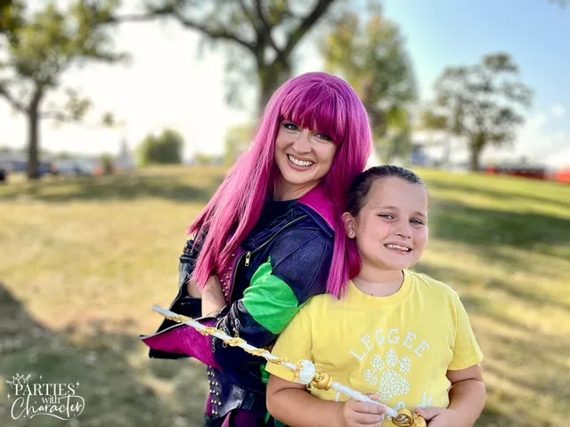 Mal outdoors with a girl in a yellow shirt holding a golden scepter