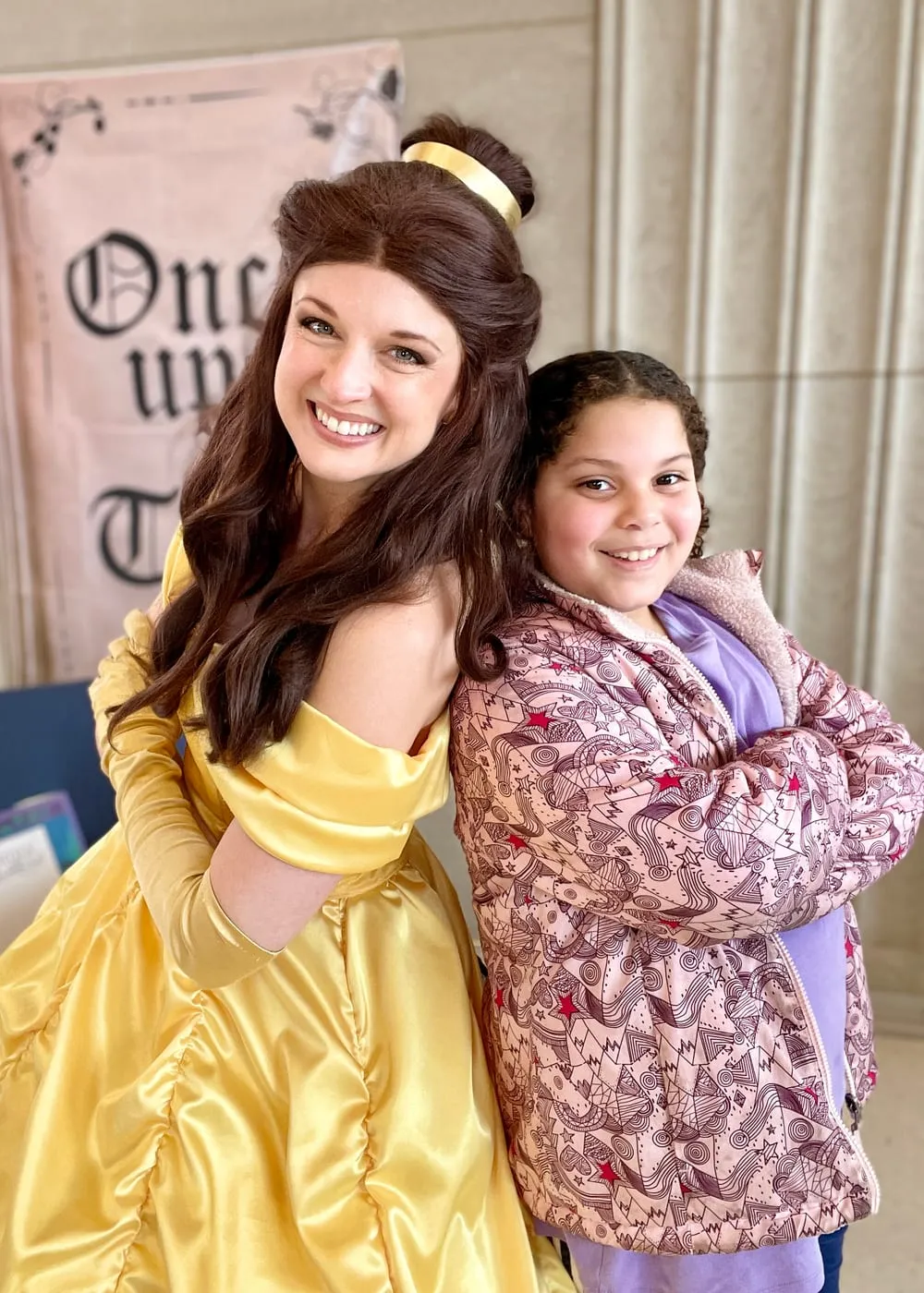 Belle posing with a girl outside a library's Once Upon a Time display