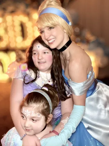 Cinderella posing with two young girls, one in a tiara with face paint