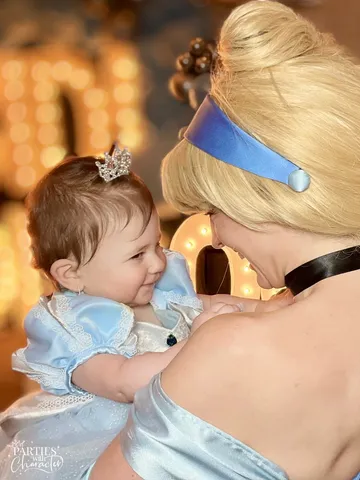Cinderella holding a smiling baby close against her shoulder at the party