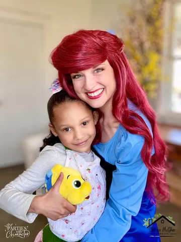 Ariel hugging a young girl holding a small yellow toy