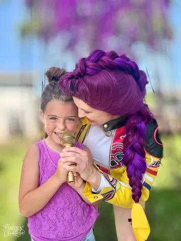 Rumi nose to nose with a girl in a purple top holding a gold microphone