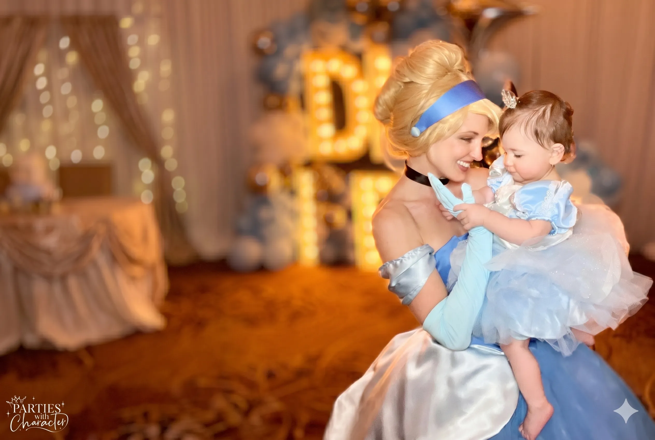 Jessica as Cinderella holding a child dressed in a matching costume at a birthday party