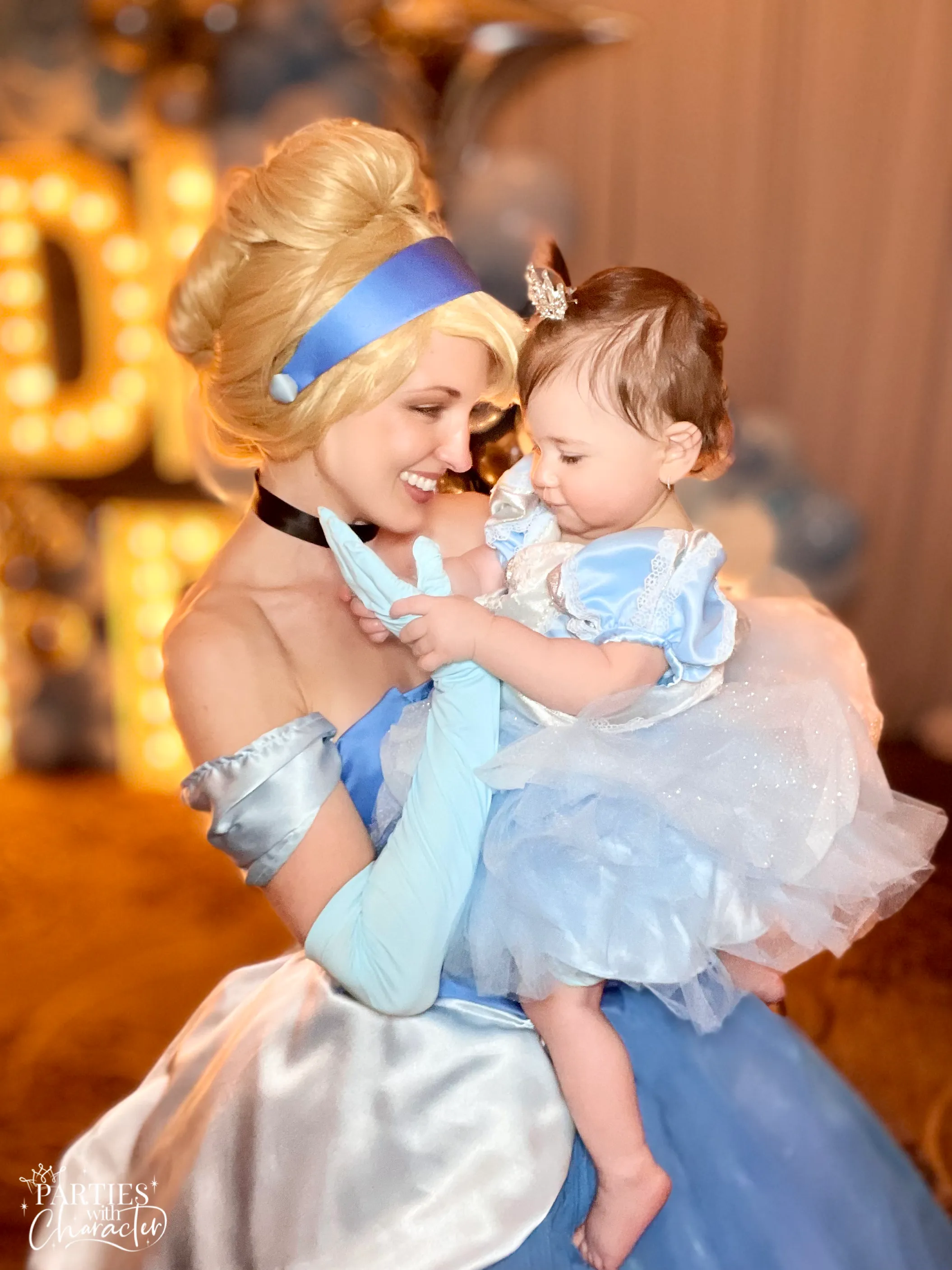 Jessica as Cinderella holding a child dressed in a matching costume at a birthday party