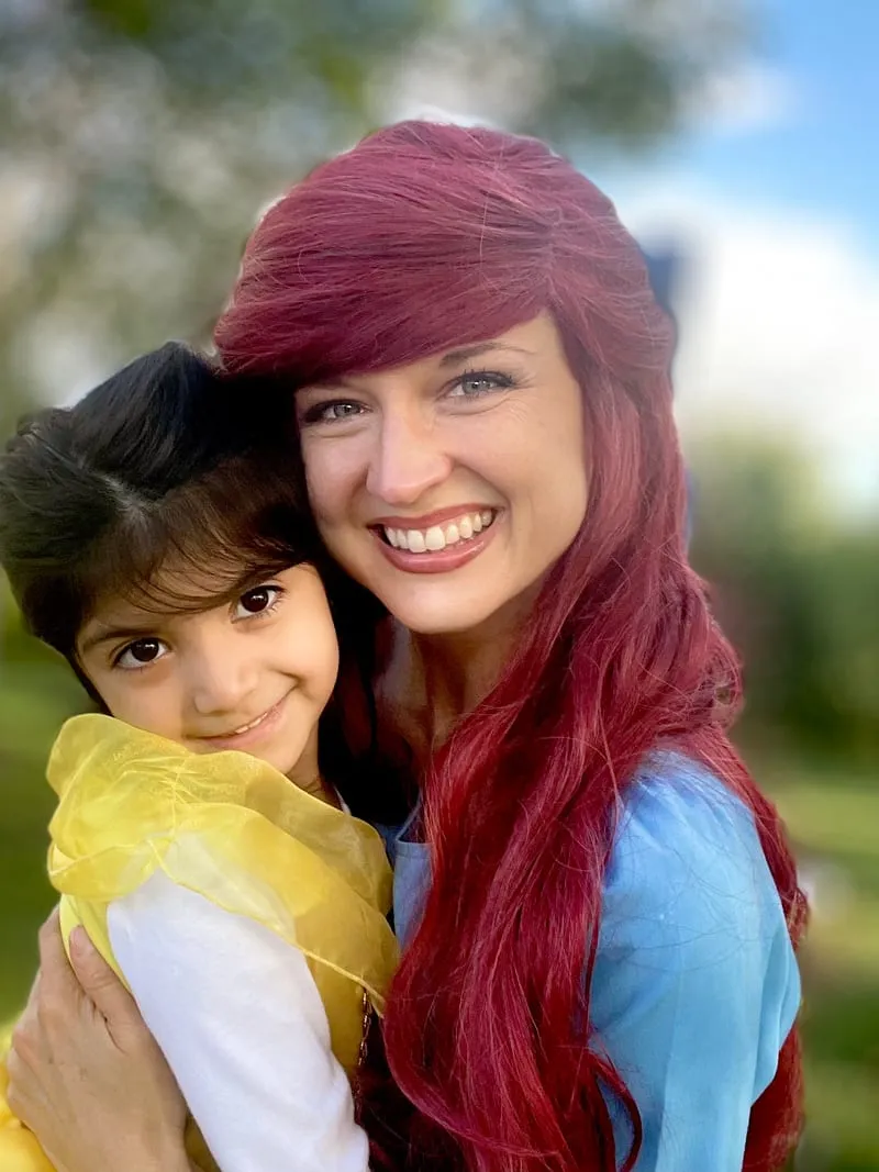 Ariel and a young girl smiling cheek to cheek outdoors
